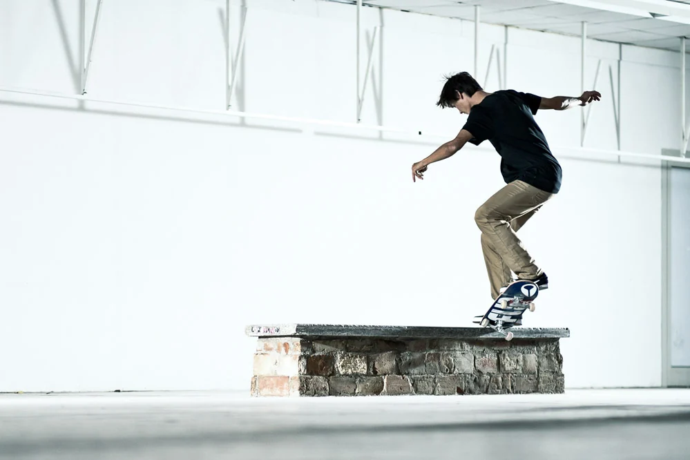 Skater w trikach na murku w jasnej hali